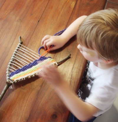 kid weaving with twig and yarn